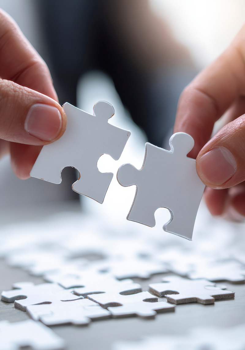 Phgoto d'une main assemblant une pièce dans un puzzle